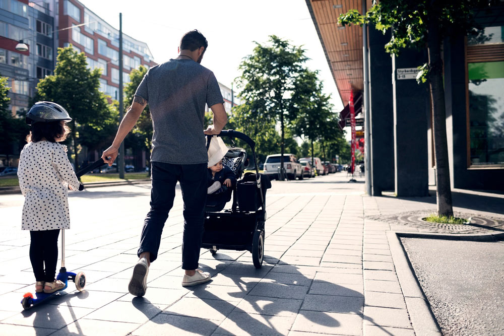 En pappa promenerar med ett barn och en barnvagn